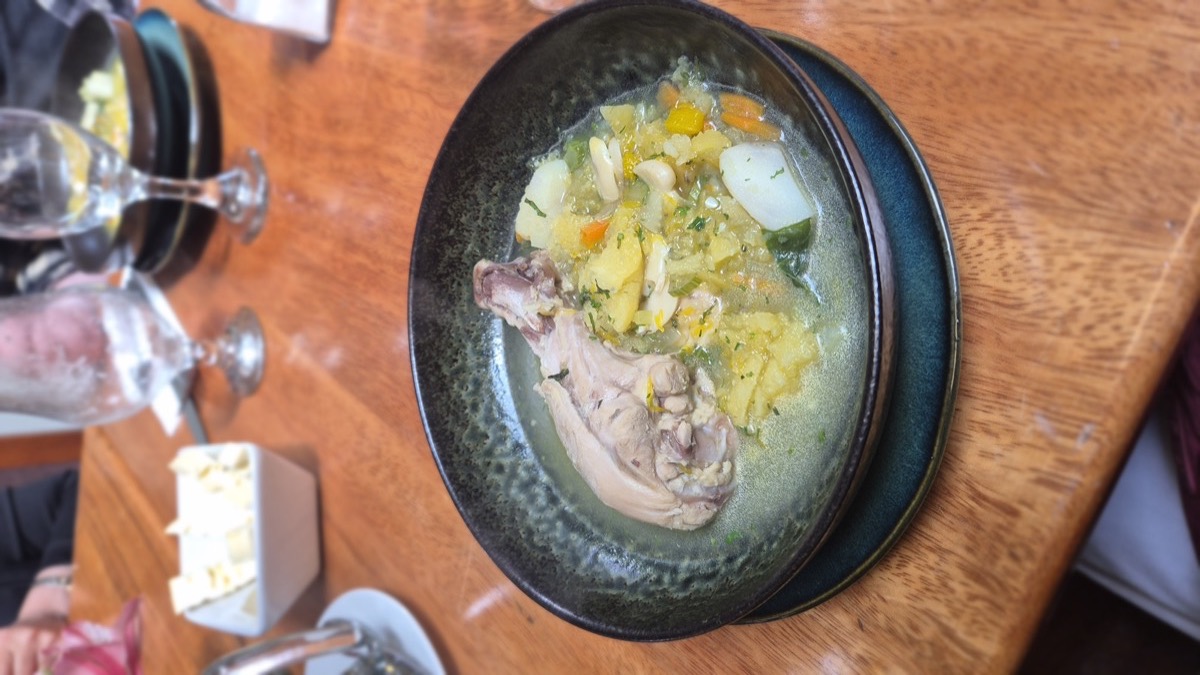 A bowl of slow-simmered chicken and vegetable stew on a wooden restaurant table
