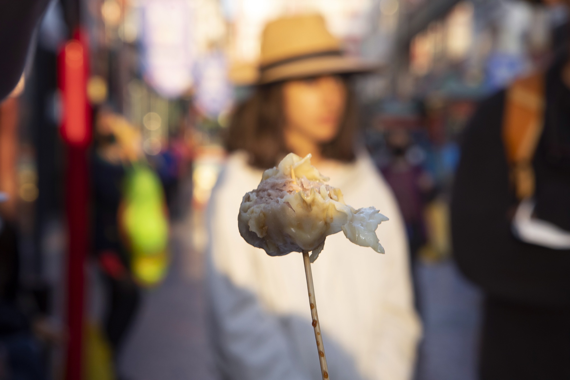 Anticucho on a skewer held up in a Lima street at golden hour