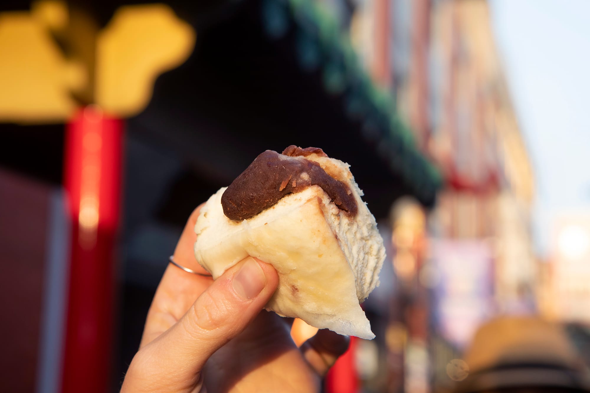 A picarón in hand on a Lima street at dusk