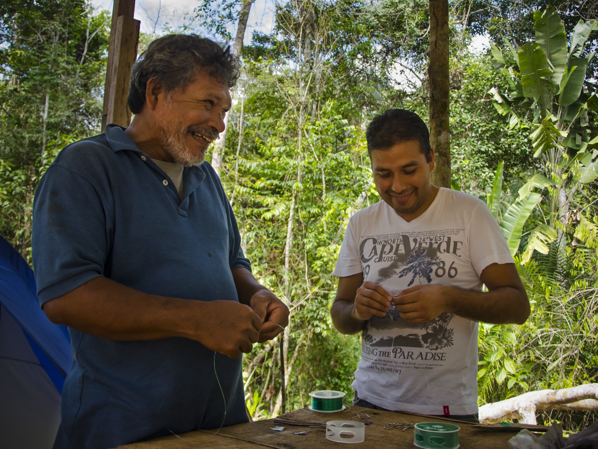 Two castañeros cracking Brazil nuts at a forest table near Puerto Maldonado
