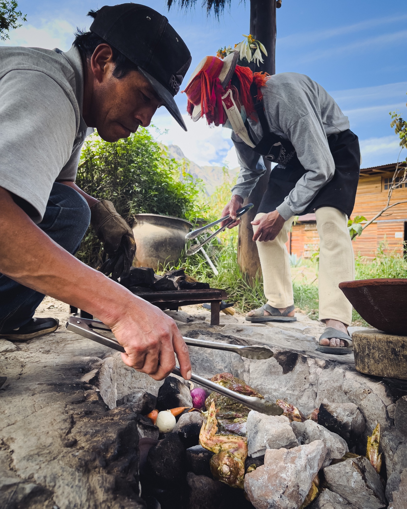 Lifting vegetables off hot stones for a pachamanca in the Sacred Valley